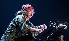 Nobuo Uematsu, bent over a music stand working on his oeuvre